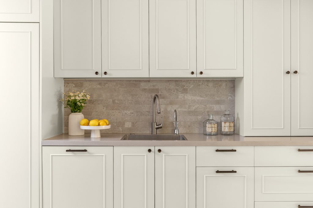 המטבח של קוקו שאנל. מטבח בהיר, חזיתות עם עיטור מקל סבא, צד כיור וארונות עליונים.