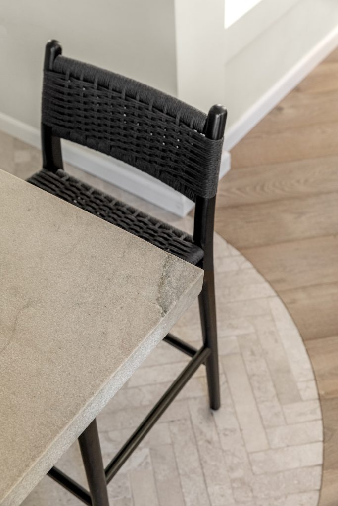 תקריב מטבח קוקו שאנל. שיש גרניט טבעי וכיסאות בר בחבל שחור. חיבור מעוגל בין אריח לפרקט